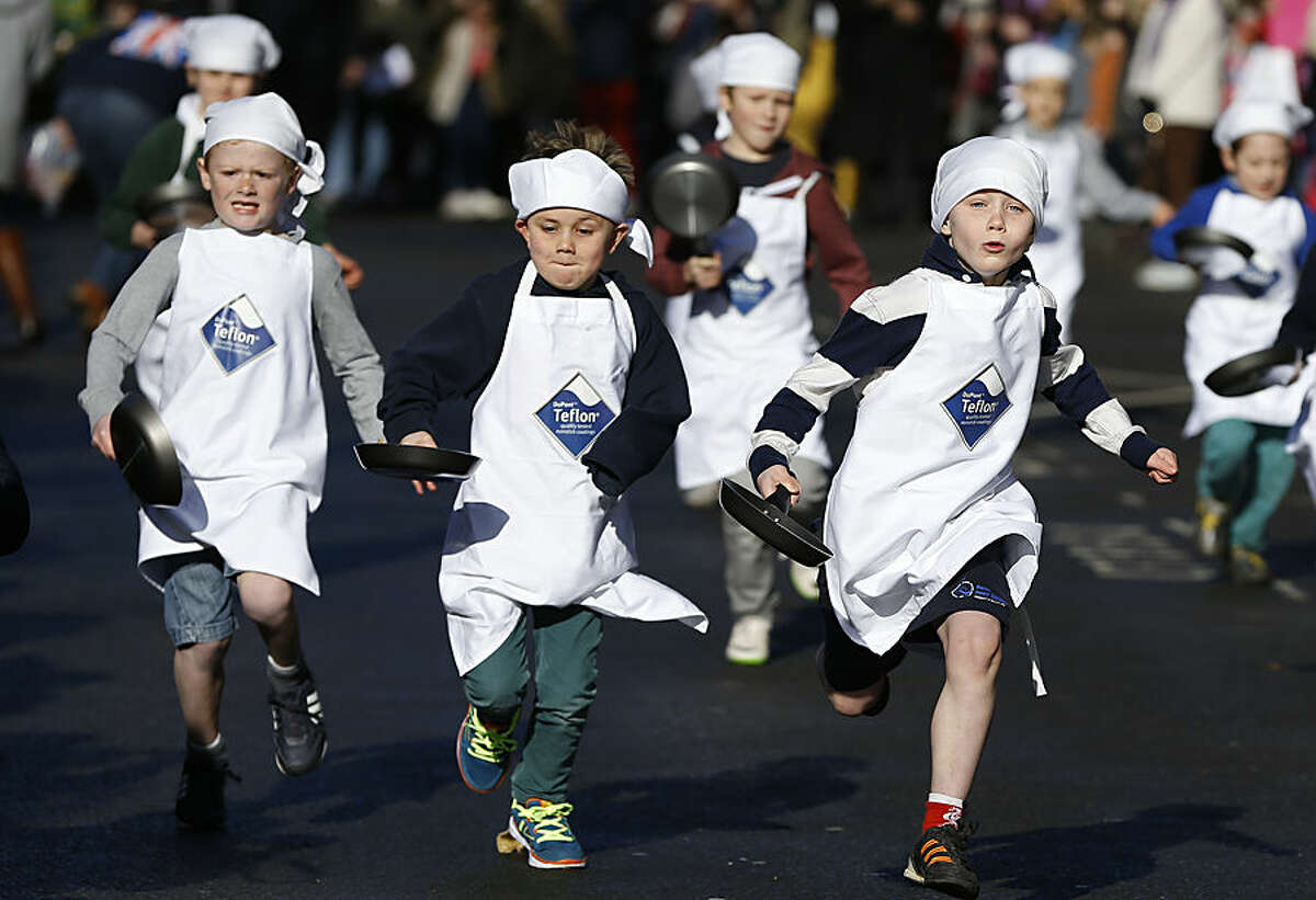 Children compete in a youngsters pancake race in Olney, Buckinghamshire in England Tuesday, Feb. 17, 2015. A pancake race has been run in the town since 1445 to mark the start of Lent. (AP Photo/Kirsty Wigglesworth)