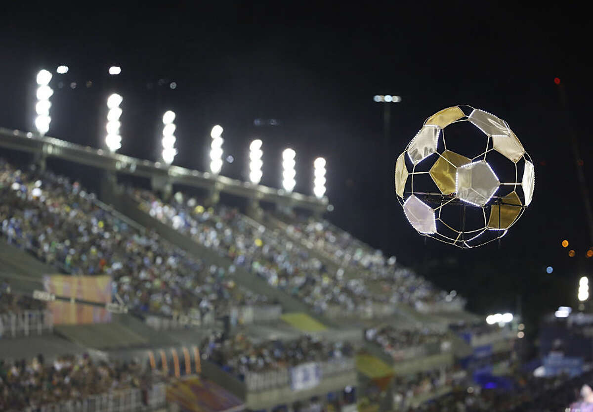 A drone, carrying a lightweight designed soccer ball, flies over the Portela samba school performers, in the Carnival parade at the Sambadrome in Rio de Janeiro, Brazil, Tuesday, Feb. 17, 2015. (AP Photo/Leo Correa)