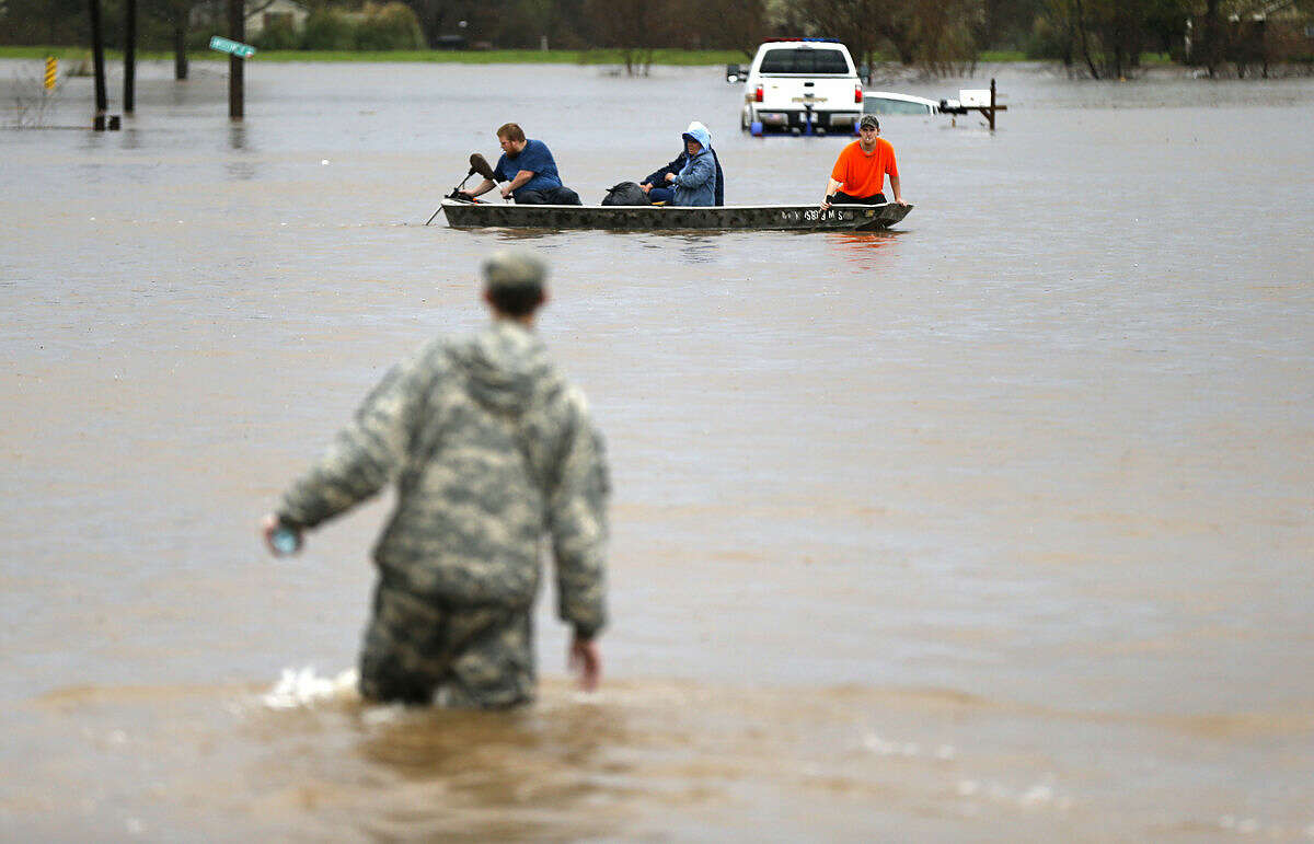 A Louisiana National Guardsman wades through water as residents are evacuated by boat through rising floodwaters in Bossier Parish, La., Thursday, March 10, 2016. (AP Photo/Gerald Herbert)