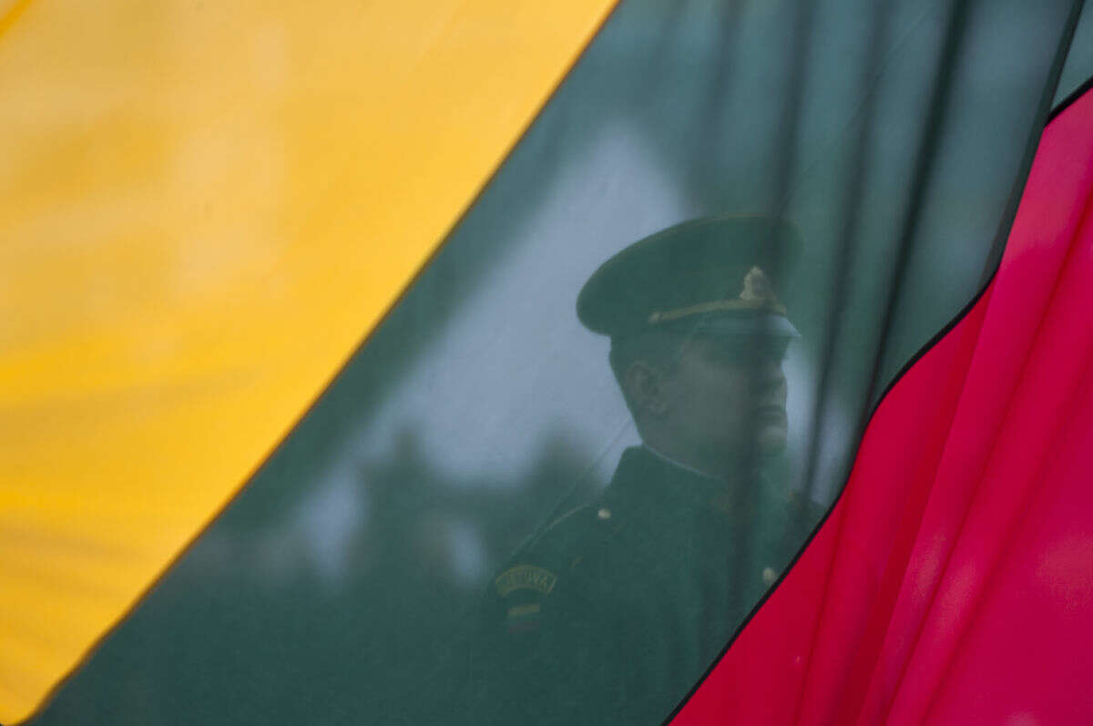 A Lithuanian soldier is seen behind a national flag being raised, during a celebration of Lithuania's independence in Vilnius, Lithuania, Friday, March 11, 2016. Lithuania celebrated the 26 anniversary of its declaration of independence from the Soviet Union on Friday, recalling the seminal events that set the Baltic nation on a path to freedom and helped lead to the collapse of the U.S.S.R. (AP Photo/Mindaugas Kulbis)
