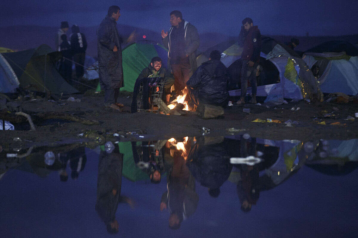 Migrants gather around a fire at the Greek border camp near Idomeni, Thursday, March 10, 2016. After nearly three days of rain, conditions in the refugee camp on the Greek-Macedonian where about 14,000 people are stranded have deteriorated significantly, with many of its residents struggling to re-pitch their small camping tents in slightly drier patches. (AP Photo/Visar Kryeziu)