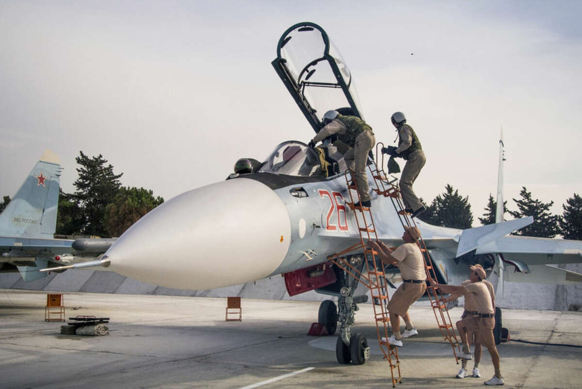 FILE - In this Oct. 22, 2015 file photo, Russian air force pilots, assisted by ground crew, climb into their fighter jet at Hemeimeem airbase, Syria. Russia's defense ministry said Tuesday, March 15, 2016, that the first group of warplanes stationed at the Russian air base in Syria has left for home following a pullout order from President Vladimir Putin.(AP Photo/Vladimir Isachenkov, File)