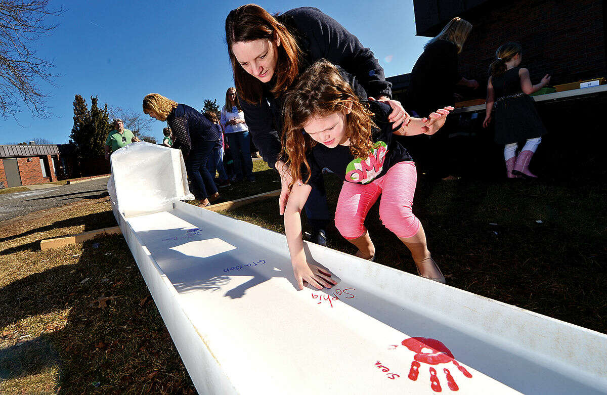 Miller-Driscoll School first-grader Sophia Solomon signs and puts her hand print on a steel beam with the help of volunteer Sarah Prevett during a ceremony celebrating the $50 million renovation project Wednesday at the school.