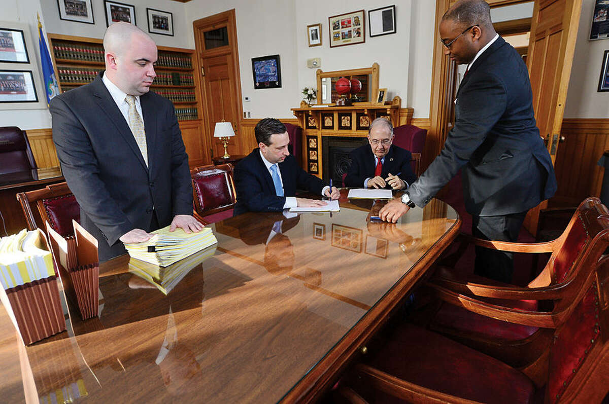 Hour photo / Erik Trautmann New Senate Majority Leader Bob Duff (D-25), second from left, signs bills with fellow senator Martin Looney before the joint legislative session and gubenatorial budget address Wednesday at the state capitol in Hartford.