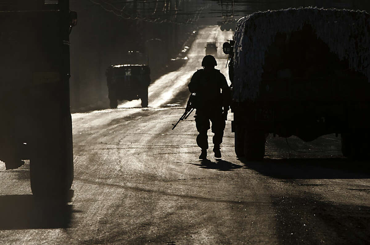 An Ukrainian soldier stands next to a broken down vehicle outside Artemivsk, Ukraine, as troops pull out of Debaltseve, Wednesday, Feb. 18, 2015. After weeks of relentless fighting, the embattled Ukrainian rail hub of Debaltseve fell Wednesday to Russia-backed separatists, who hoisted a flag in triumph over the town. The Ukrainian president confirmed that he had ordered troops to pull out and the rebels reported taking hundreds of soldiers captive.(AP Photo/Vadim Ghirda)