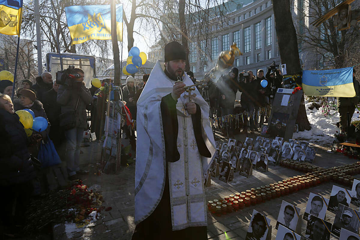 An Orthodox priest leads a service at a memorial dedicated to people who died in clashes with security forces in Kiev, Wednesday, Feb. 18, 2015. Municipal workers are preparing the square to commemorate the Maidan protest movement and the events which took place in late Feb. 2014 that led to the departure of former Ukrainian President Victor Yanukovich and the formation of a new government. (AP Photo/Sergei Chuzavkov)