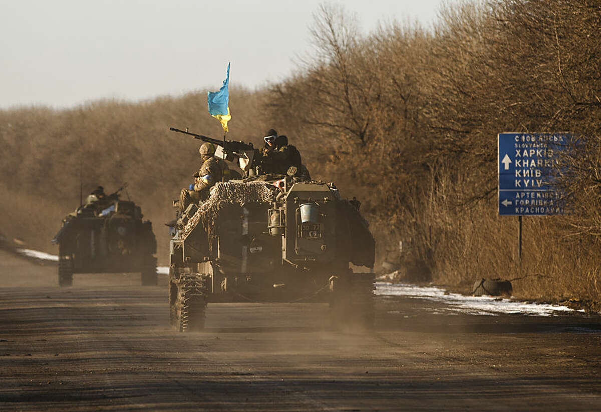 Ukrainian troops ride on an armored vehicle outside Artemivsk, Ukraine, while pulling out of Debaltseve, Wednesday, Feb. 18, 2015. After weeks of relentless fighting, the embattled Ukrainian rail hub of Debaltseve fell Wednesday to Russia-backed separatists, who hoisted a flag in triumph over the town. The Ukrainian president confirmed that he had ordered troops to pull out and the rebels reported taking hundreds of soldiers captive. (AP Photo/Vadim Ghirda)