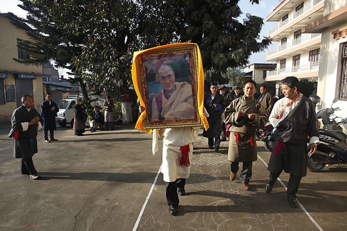 A Tibetan man carries a portrait of spiritual leader the Dalai Lama during Tibetan New Year, or Losar, inside the Tibetan Refugee Camp in Lalitpur, Nepal, Thursday, Feb. 19, 2015. Tibetans across the world marked the arrival of the New Year with prayers and festivities. (AP Photo/Niranjan Shrestha)