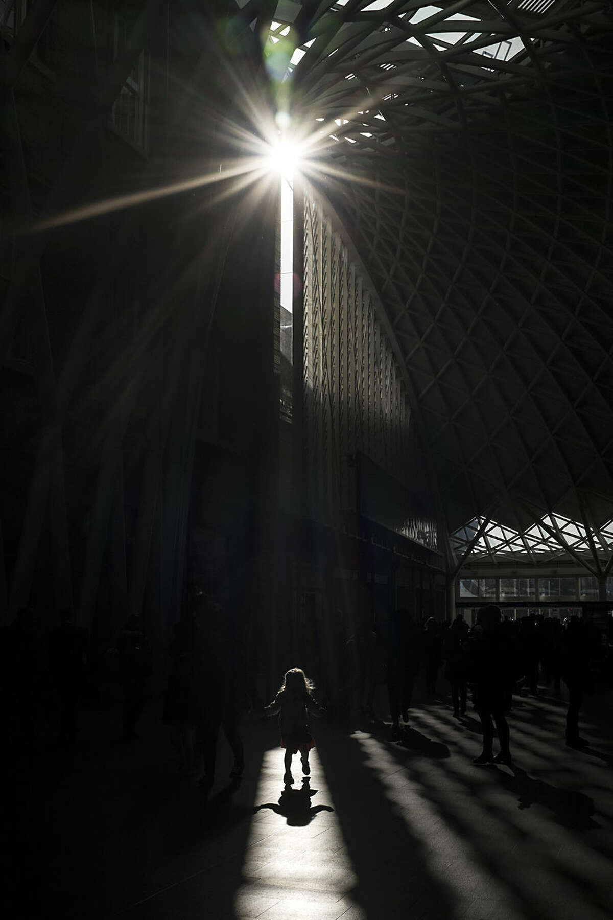 A girl walks in a shaft of light on the main concourse at King's Cross railway station, London, Wednesday, Feb. 18, 2015. More than 29 million passengers annually rely on mainline train services from King's Cross, according to the British Office of Rail Regulation, making it the ninth busiest station in the country. (AP Photo/David Azia)