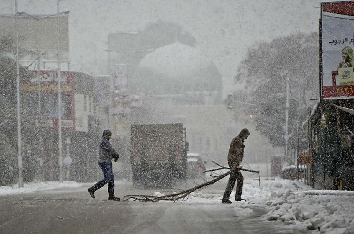Palestinians cross a snow-blanketed street in the West Bank City of Nablus, Friday, Feb. 20, 2015. A heavy winter storm hit parts of the Middle East on Friday, shutting down roads leading in and out of Jerusalem and sprinkling areas of Israel's desert with a rare layer of white. Snow also fell in parts of the West Bank, Lebanon, Jordan and Syria as a cold front swept through the region. (AP Photo/Majdi Mohammed)