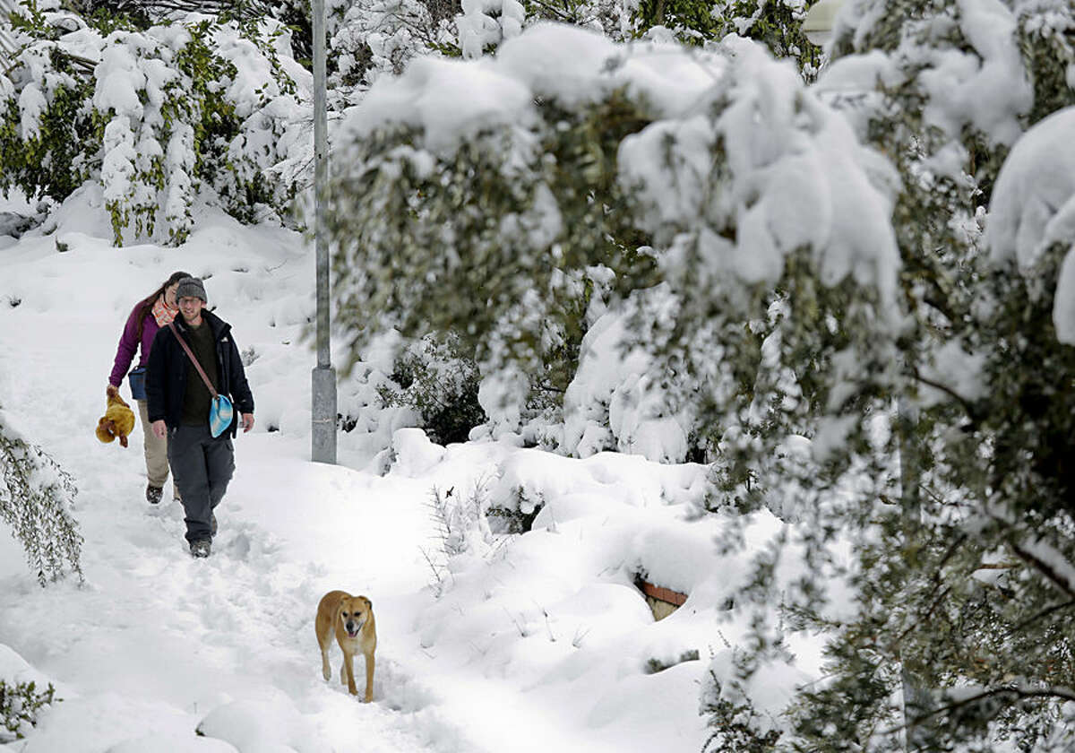 A couple walk their dog in Jerusalem, Friday, Feb. 20, 2015. A heavy winter storm descended on parts of the Middle East on Friday, with snow forcing the closure of all roads leading in and out of Jerusalem and sprinkling Israel's desert with a rare layer of white. (AP Photo/Dusan Vranic)