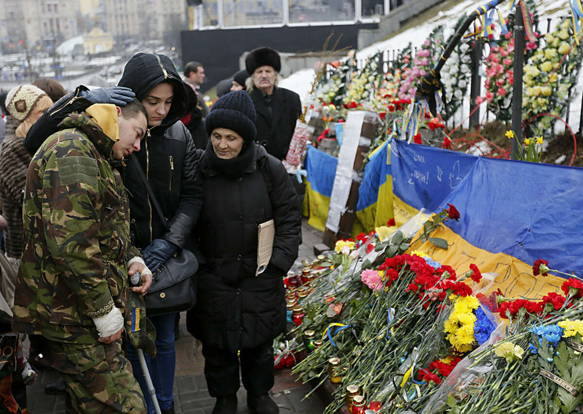 People pay their respects in honor of the "Heavenly Hundred" on Independence Square in Kiev, Ukraine, Friday, Feb. 20, 2015. The "Heavenly Hundred" is what Ukrainians in Kiev call those who died during months of anti-government protests in 2013-14. The grisliest day was a year ago Friday _ Feb. 20, 2014 _ when sniper fire tore through crowds on the capital's main square, killing more than 50 people. A year later, so much has changed. Russia has annexed Ukraine’s Crimean Peninsula, Ukraine has a new president and government, and the country is embroiled in a war in the east with Russia-backed separatists that has killed over 5,600 people and forced a million to flee.(AP Photo/Sergei Chuzavkov)