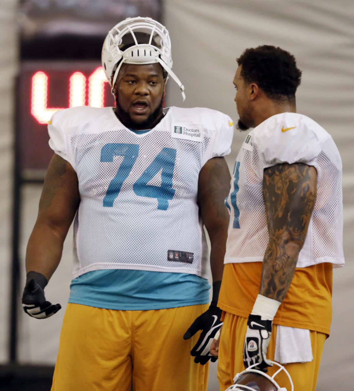 FILE - In this Nov. 4, 2013, file photo, Miami Dolphins guard John Jerry (74) talks with center Mike Pouncey during NFL football practice in Davie, Fla. Dolphins offensive lineman Jonathan Martin was subjected to "a pattern of harassment" that included racist slurs and vicious sexual taunts about his mother and sister by three teammates, according to a report ordered by the NFL. The report said Richie Incognito, who was suspended by the team in November, and fellow offensive linemen Jerry and Pouncey harassed Martin. (AP Photo/Lynne Sladky)