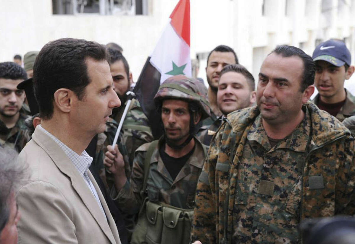 FILE - In this file photo taken on Sunday April 20, 2014 and released by the Syrian official news agency SANA, Syrian President Bashar Assad, left, talks to government soldiers during his visit to the Christian village of Maaloula, near Damascus, Syria. (SANA via AP, File)