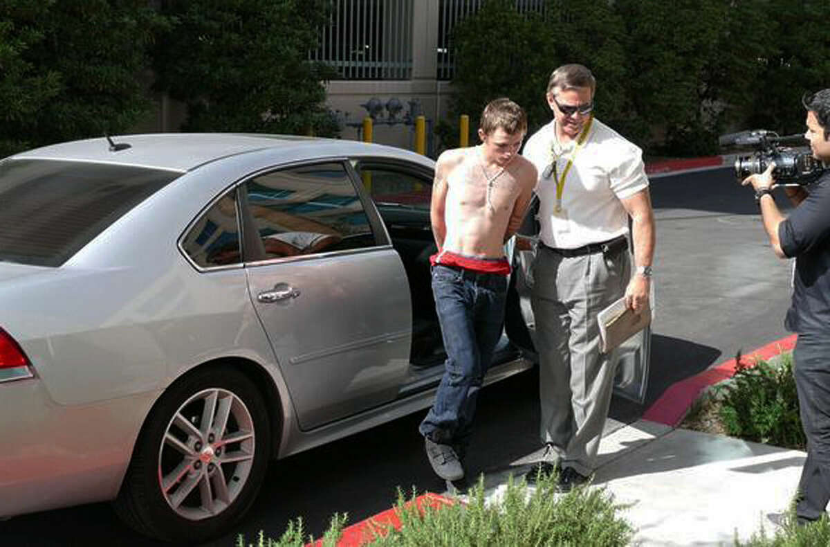 In this photo released by the Las Vegas Metropolitan Police Department, an unidentified police official leads Erich Nowsch, 19, from a car to police headquarters for questioning in Las Vegas, Thursday, Feb. 19, 2015. Nowsch was arrested on suspicion of murder after SWAT teams surrounded his home a block away from the residence of Tammy Meyers who was killed in a mysterious road-rage incident last week. (AP Photo/Las Vegas Metropolitan Police Department)