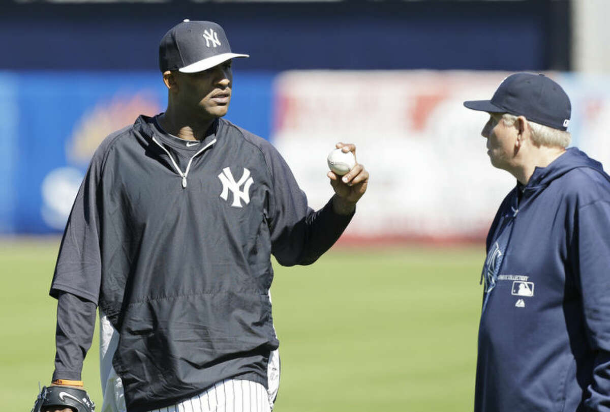 New York Yankees starting pitcher CC Sabathia, left, talks with pitching coach Larry Rothschild, right, during spring training baseball practice Friday, Feb. 14, 2014, in Tampa, Fla. (AP Photo/Charlie Neibergall)