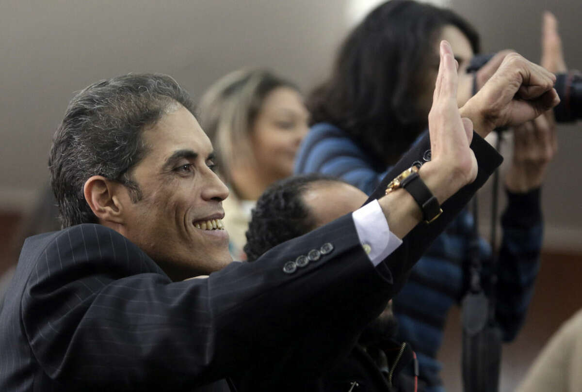 Khaled Dawoud, spokesman for the liberal al-Dustour party, waves to 21 activists sentenced by an Egyptian court to prison terms over an unauthorized street protest in 2013, at a Cairo court, Egypt, Monday, Feb. 23, 2015. The court sentenced Alaa Abd el-Fattah, an icon of the country's 2011 revolt to five years in prison Monday, showing authorities' determination to continue to stifle dissent despite promises by its president to release "wrongly jailed youths." Another defendant, Ahmed Abdel Rahman, was also given five years. The others were sentenced to three years. (AP Photo/Amr Nabil)