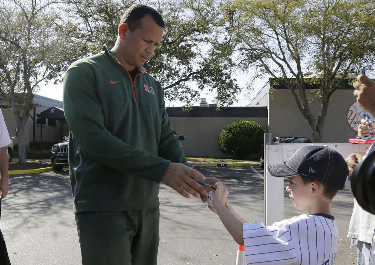 New York Yankees' Alex Rodriguez, left, signs autographs for fans following a workout for spring training baseball, at the Yankees minor league facility, Monday, Feb. 23, 2015, in Tampa, Fla. The official full squad workouts begin Feb. 26. (AP Photo/Lynne Sladky)