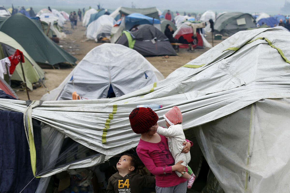 Migrant children stand in front of tents in the makeshift refugee camp at the northern Greek border point of Idomeni, Greece, Wednesday, March 23, 2016. The U.N. refugee agency pulled out staff Tuesday from facilities on Lesbos and other Greek islands being used to detain refugees and migrants as an international deal with Turkey came under further strain. (AP Photo/Darko Vojinovic)