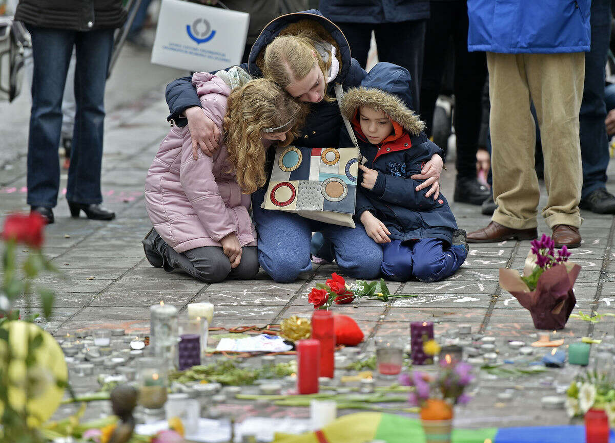 A woman and children sit and mourn for the victims of the bombings at the Place de la Bourse in the center of Brussels, Wednesday, March 23, 2016. Bombs exploded yesterday at the Brussels airport and one of the city's metro stations Tuesday, killing and wounding scores of people, as a European capital was again locked down amid heightened security threats. (AP Photo/Martin Meissner)