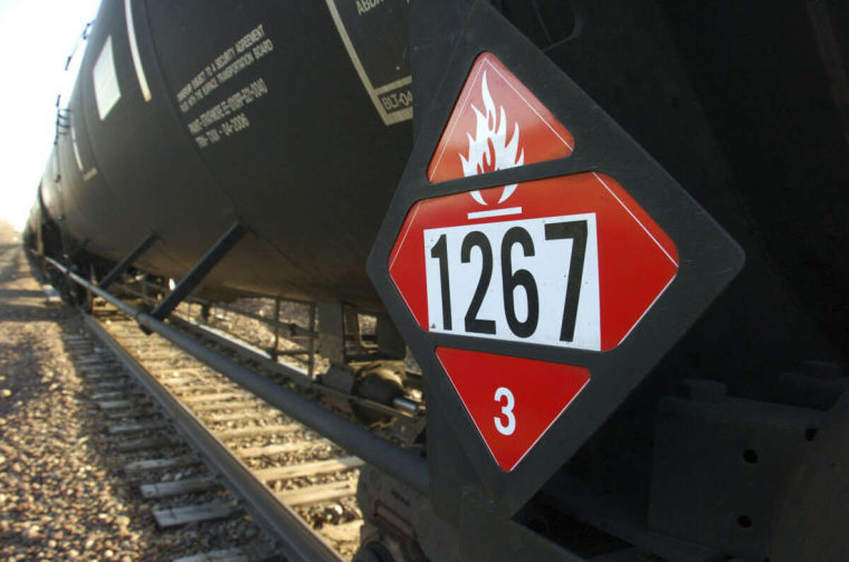 FILE - In this Nov. 6, 2013, file photo, a warning placard appears on a tank car carrying crude oil near a loading terminal in Trenton, N.D. Trains carrying millions of gallons of explosive liquids, including crude oil, are likely to continue rolling through major cities despite the government?’s urging to steer the shipments around population centers in the wake of several accidents, according to industry experts. (AP Photo/Matthew Brown, File)