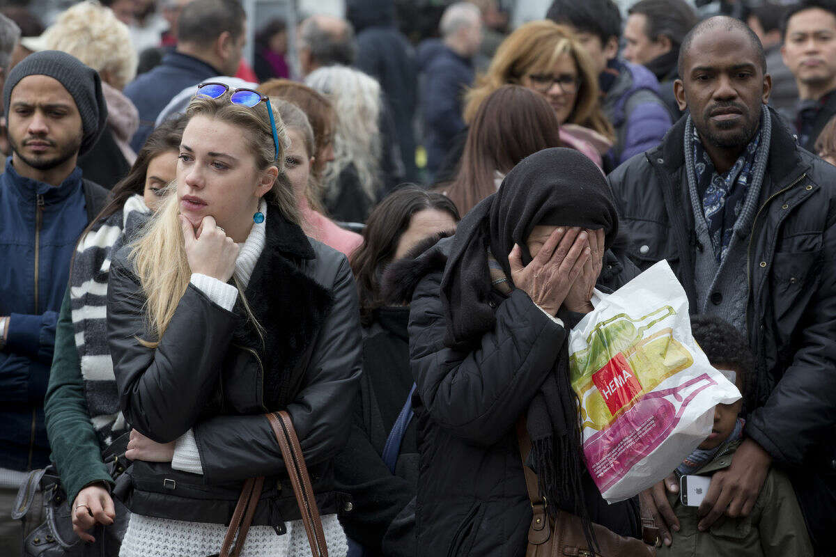 A muslim woman prays, second right, as she and other people gathered to observe a minute of silence and mourn for the victims of the bombings at the Place de la Bourse in the center of Brussels, Belgium, Thursday, March 24, 2016. The Islamic State group has trained at least 400 fighters to target Europe in deadly waves of attacks, deploying interlocking terror cells like the ones that struck Brussels and Paris with orders to choose the time, place and method for maximum carnage. (AP Photo/Peter Dejong)