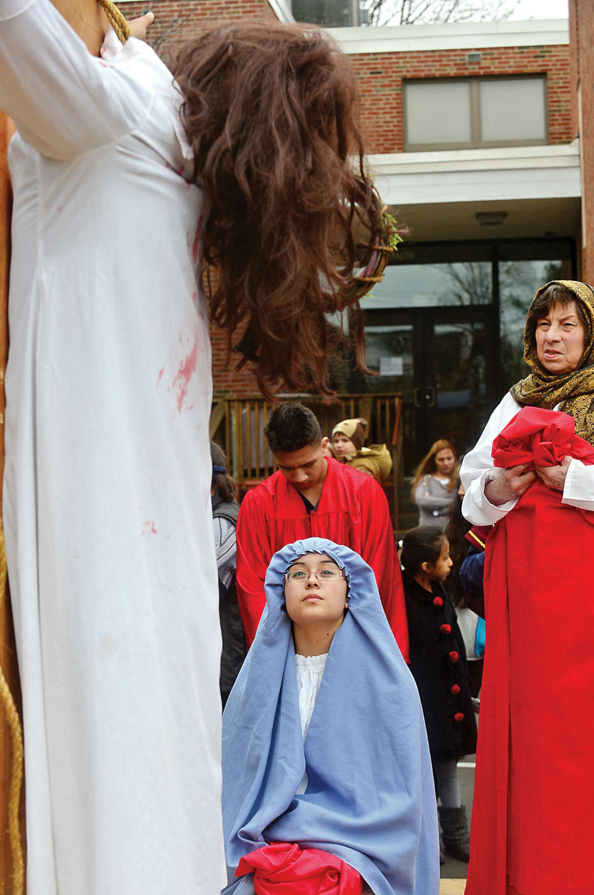 Hour photo / Erik Trautmann Alexandra Garcia, 15, portrays Mary, bottom left, as nearly 100 parishioners of St. Joseph Church observe the Living Stations of the Cross at the church in South Norwalk on Good Friday.