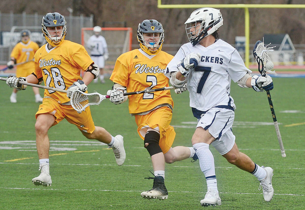 Hour photo / Erik Trautmann Staples High School Lacrosse player #7 Ross Goldberg gets by Weston's Andre DiPasquale and John Cannon during Staples rout Saturday.