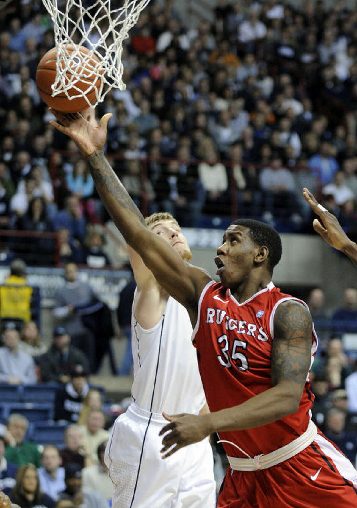 Rutgers' Greg Lewis (35) drives past Connecticut's Niels Giffey (5)during the first half of an NCAA college basketball game in Storrs, Conn., Wednesday, March 5, 2014. (AP Photo/Fred Beckham)