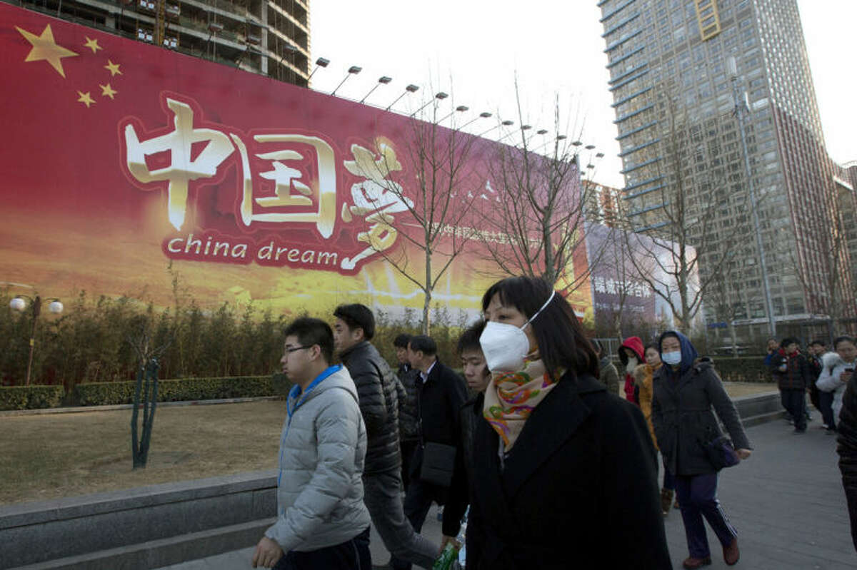 Chinese women wearing masks walk past a Chinese government propaganda billboard with the words "China Dream" in Beijing, China, Thursday, March 6, 2014. Combatting pollution has shot up the agenda of the ruling Communist Party, which for years pushed for rapid economic development with little concern about the environmental impact. Under public pressure to reduce the air pollution that blankets Beijing and cities across China, the country's leaders are rebalancing their priorities. (AP Photo/Ng Han Guan)