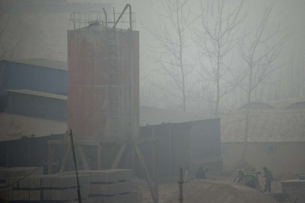 In this photo taken on Wednesday, Feb. 26, 2014, men work in a cement plant on a severely polluted day in Shijiazhuang, in northern China's Hebei province. Combatting pollution has shot up the agenda of the ruling Communist Party, which for years pushed for rapid economic development with little concern about the environmental impact. Under public pressure to reduce the air pollution that blankets Beijing and cities across China, the country's leaders are rebalancing their priorities.(AP Photo/Alexander F. Yuan)