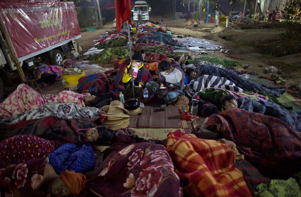 Students protesters who have been staging a sit-in since March 3, lie on the ground covered in blankets as two-others check their mobile phones in Letpadan, 140 kilometers (90 miles) north of the country's main city Yangon, Myanmar, at the dawn of Saturday March 7, 2015. On Friday, March 6 in another location in Letpadan police cracked down on student protesters opposing Myanmar's new education law, roughly grabbing demonstrators and loading them onto trucks in the third such clampdown in as many days. More protests were held on later on Friday in solidarity with the protesting students and condemning the crackdowns in other towns in Myanmar. (AP Photo/Gemunu Amarasinghe)