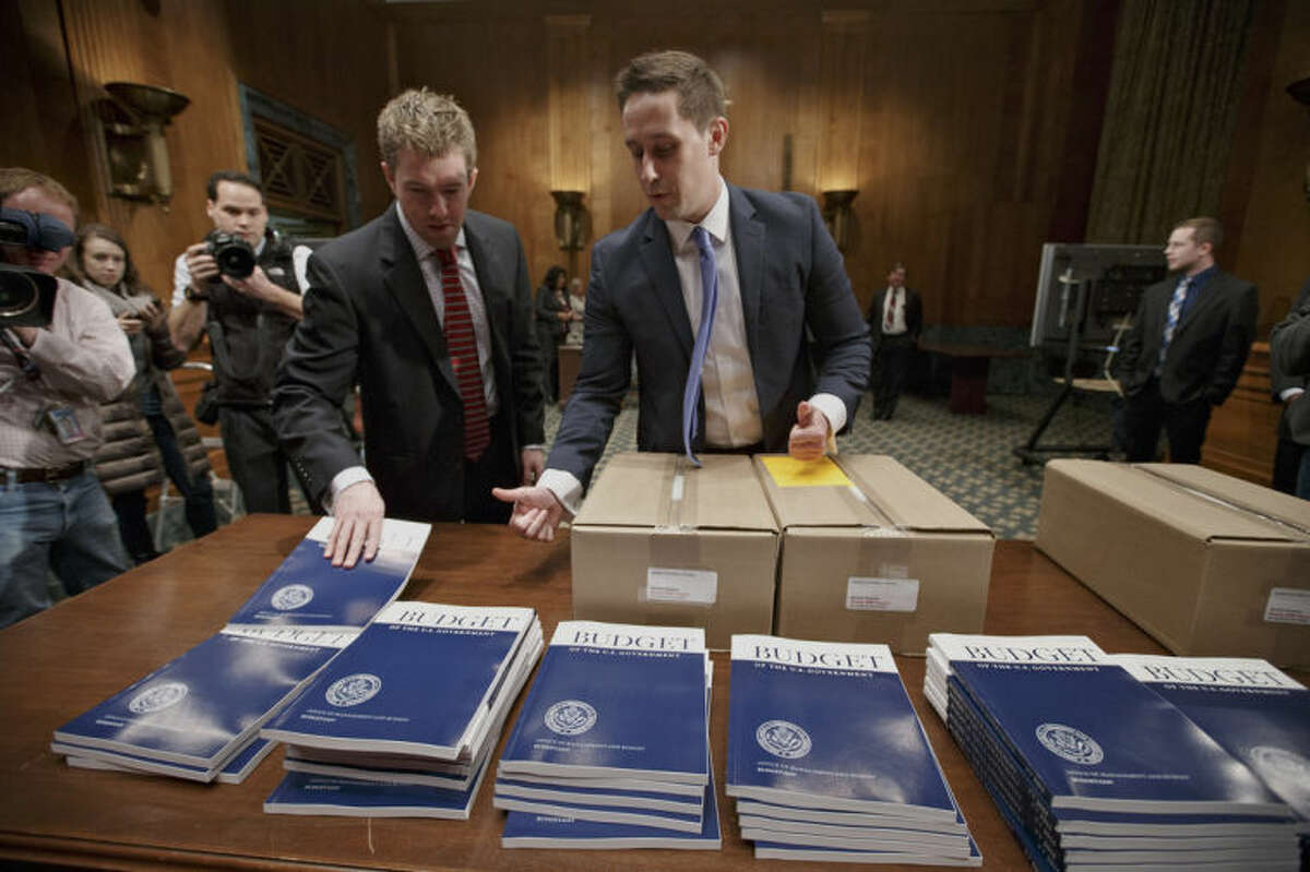 Copies of President Barack Obama?’s proposed fiscal 2015 budget are set out for distribution by Senate Budget Committee Clerk Adam Kamp, center, on Capitol Hill in Washington, Tuesday, March 4, 2014. President Barack Obama is unwrapping a nearly $4 trillion budget that gives Democrats an election-year playbook for fortifying the economy and bolstering Americans' incomes. It also underscores how pressure has faded to launch bold, new attacks on federal deficits. (AP Photo/J. Scott Applewhite)