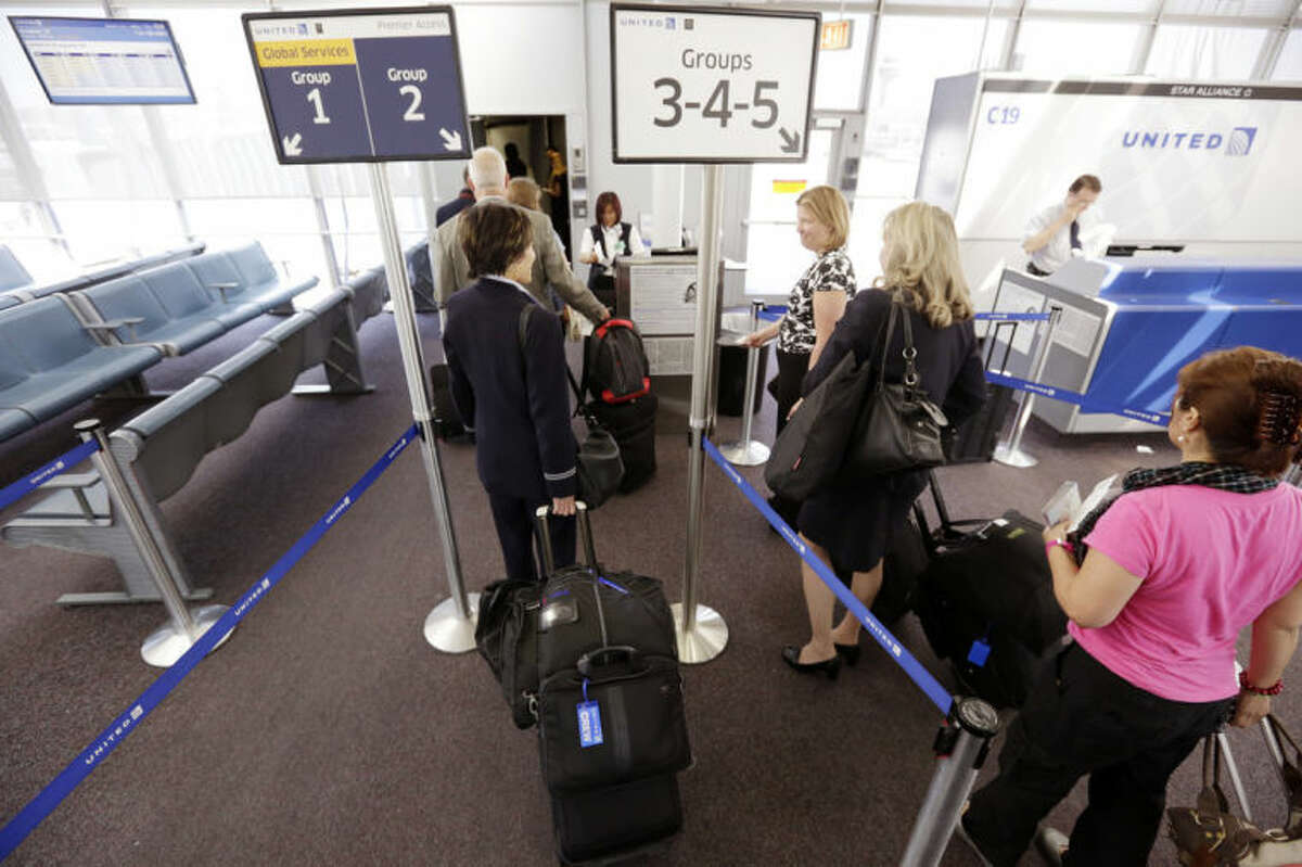 FILE - In this May 8, 2013 file photo, groups of passengers wait at a United Airlines gate to board a flight in separate numbered lanes at O'Hare International Airport in Chicago. In February 2014, United Airlines installed new bag sizers at airports and emailed its frequent fliers, reminding them of its rules (AP Photo/M. Spencer Green)