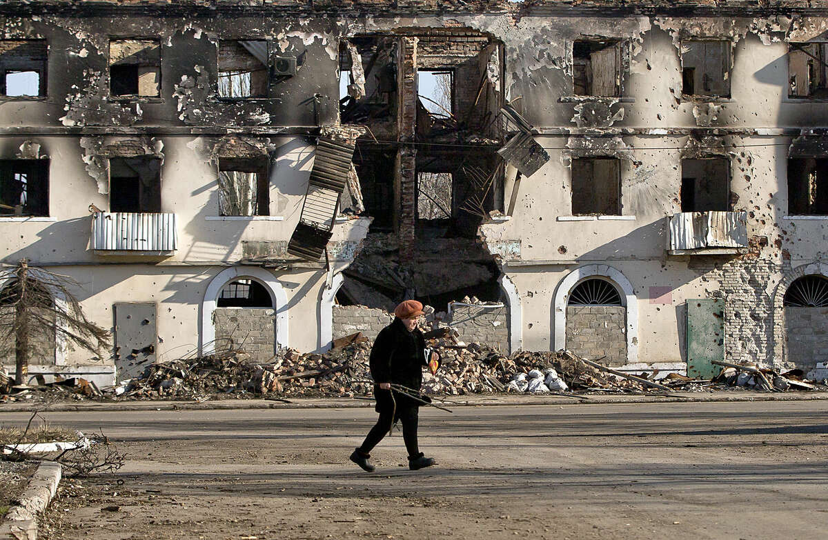 An elderly woman walks by a destroyed building in Vuhlehirsk, Ukraine, Monday, March 9, 2015. More than 6,000 people have died in eastern Ukraine since the start of the conflict almost a year ago that has led to a "merciless devastation of civilian lives and infrastructure," according to the U.N. human rights office. (AP Photo/Vadim Ghirda)