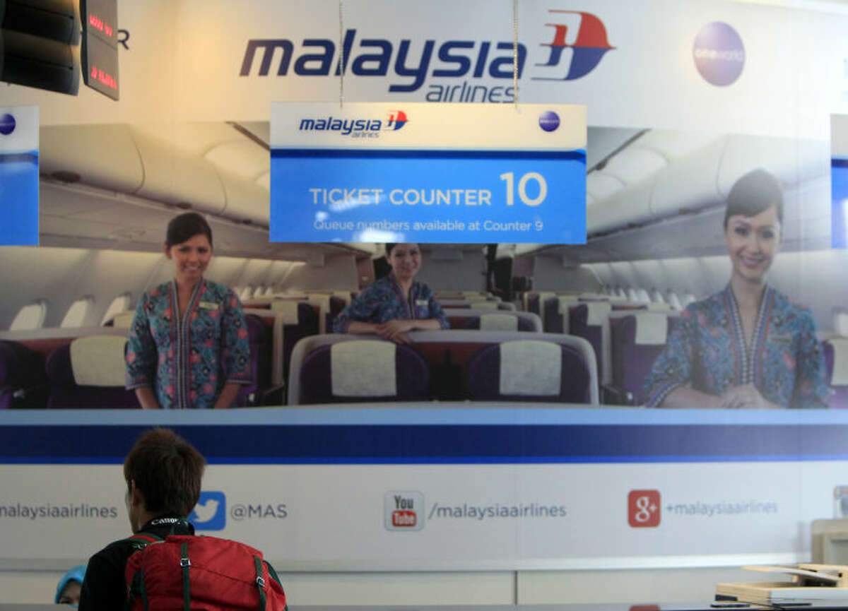 A passenger checks information at a Malaysia Airlines booth at Kuala Lumpur International Airport in Sepang, outside Kuala Lumpur, Malaysia, Saturday, March 8, 2014. A Malaysia Airlines Boeing 777-200 carrying 239 people lost contact with air traffic control early Saturday morning on a flight from Kuala Lumpur to Beijing, and international aviation authorities still hadn't located the jetliner several hours later. (AP Photo/Lai Seng Sin)