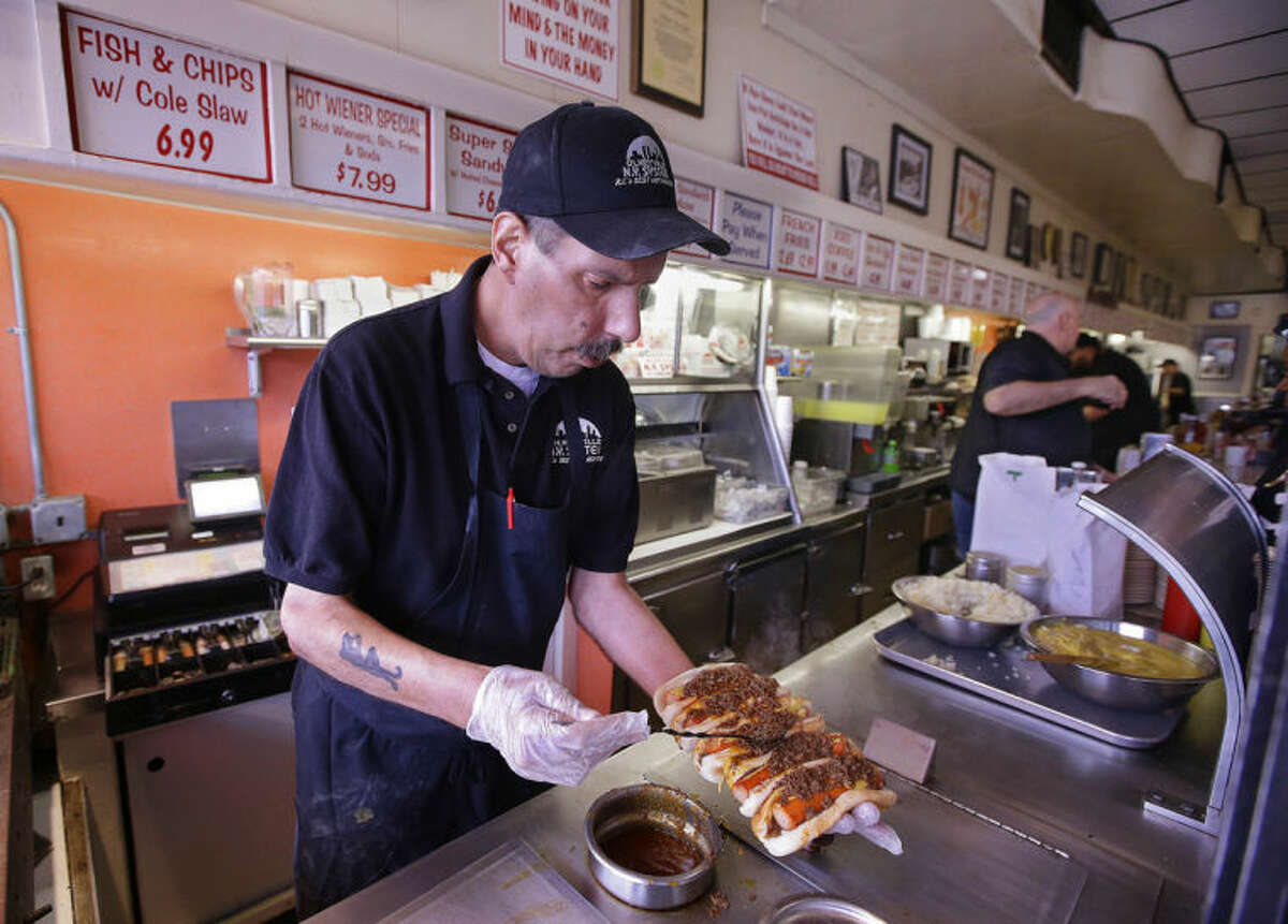 In this Monday, March 3, 2014 photo Sal O'Brien holds wieners he preps "all the way" for a customer's order at Olneyville New York System of Providence in Providence, RI. The James Beard Foundation named the Rhode Island restaurant one of five "American Classics" this year as best known for hot wieners, also called hot dogs. (AP Photo/Stephan Savoia)