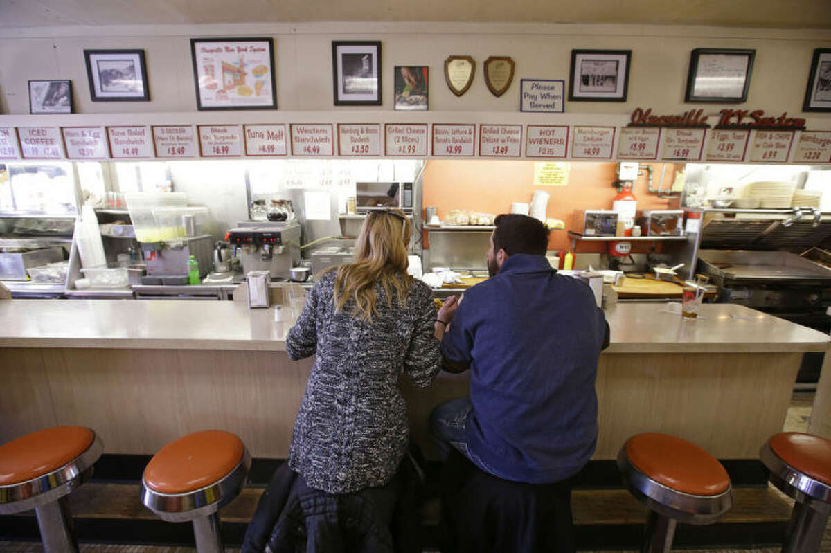 In this Monday, March 3, 2014 photo Holly Wilson and Ioanni Degaitas eat a lunch of two hot wieners, a loaded cheese burger, a grilled cheese sandwich with bacon and tomato, chile cheese fries, eggs, home fires, coffee milk and black coffee at Olneyville New York System of Providence in Providence, RI. The James Beard Foundation named the Rhode Island restaurant one of five "American Classics" this year as best known for hot wieners, also called hot dogs. (AP Photo/Stephan Savoia)