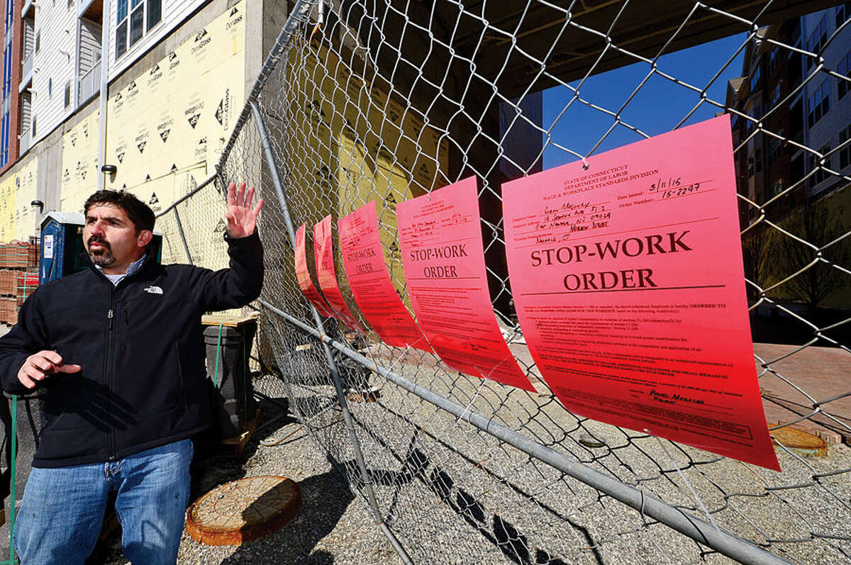 Hour photo / Erik Trautmann Ted Duarte, Senior Organizer for New England Regional Council of Carperters, points out the stop work orders posted by the Connecticut Department of Labor for several contractors engaged in the Waypointe redevelopment project on Orchard St. Thursday.