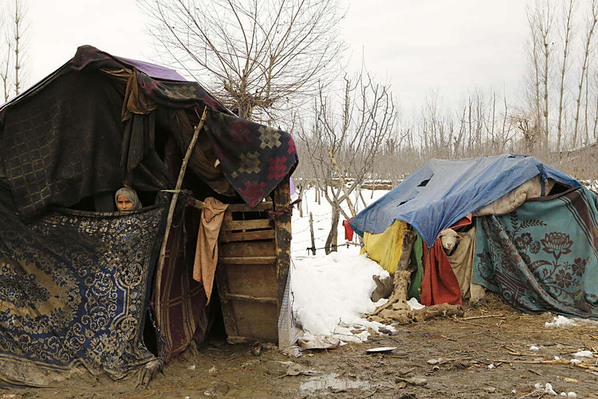 A young Kashmiri Bakarwal nomad girl looks out from inside her temporary camp, with a sheep in the adjoining tent at Haal village, some 52 Kilometers (33 miles) south of Srinagar, India, Wednesday, March 18, 2015. The Jammu-Srinagar highway, connecting the Kashmir valley to the rest of the country, remained closed for the fourth consecutive day Wednesday following heavy rain and snowfall at some places. (AP Photo/Mukhtar Khan)