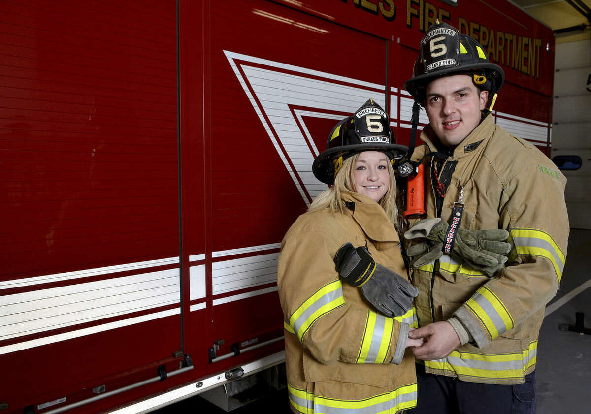 In this Feb. 12, 2015 file photo, Shaker Pines Fire Department, firefighters Melissa Greczkowski, left, and her fiancé Damian McCartney pose for a photograph at the firehouse in Enfield, Conn. McCartney planned to propose during an elaborate, staged training drill outdoors. But when the first of 2015’s blizzards struck, they had to revert to an alternative plan indoors. (AP Photo/The Hartford Courant, Marc-Yves Regis I)