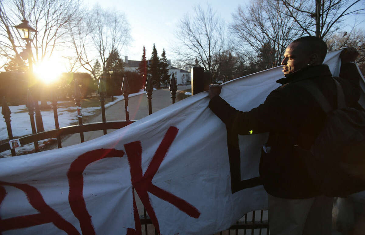 A protester hangs a banner reading "Black Lives Matter" on the gate outside of the Governor's Mansion during a protest of the police killing of Tony Robinson in Maple Bluff, Wis., Wednesday, March 11, 2015. (AP Photo/Wisconsin State Journal, Michael P. King)