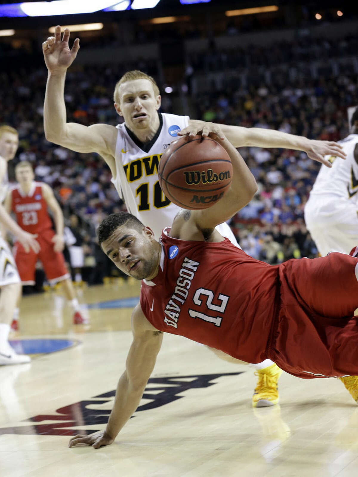 Davidson's Jack Gibbs (12) continues to dribble as he tumbles to the floor in front of Iowa's Mike Gesell during the second half of an NCAA tournament college basketball game in the Round of 64 in Seattle, Friday, March 20, 2015. (AP Photo/Elaine Thompson)