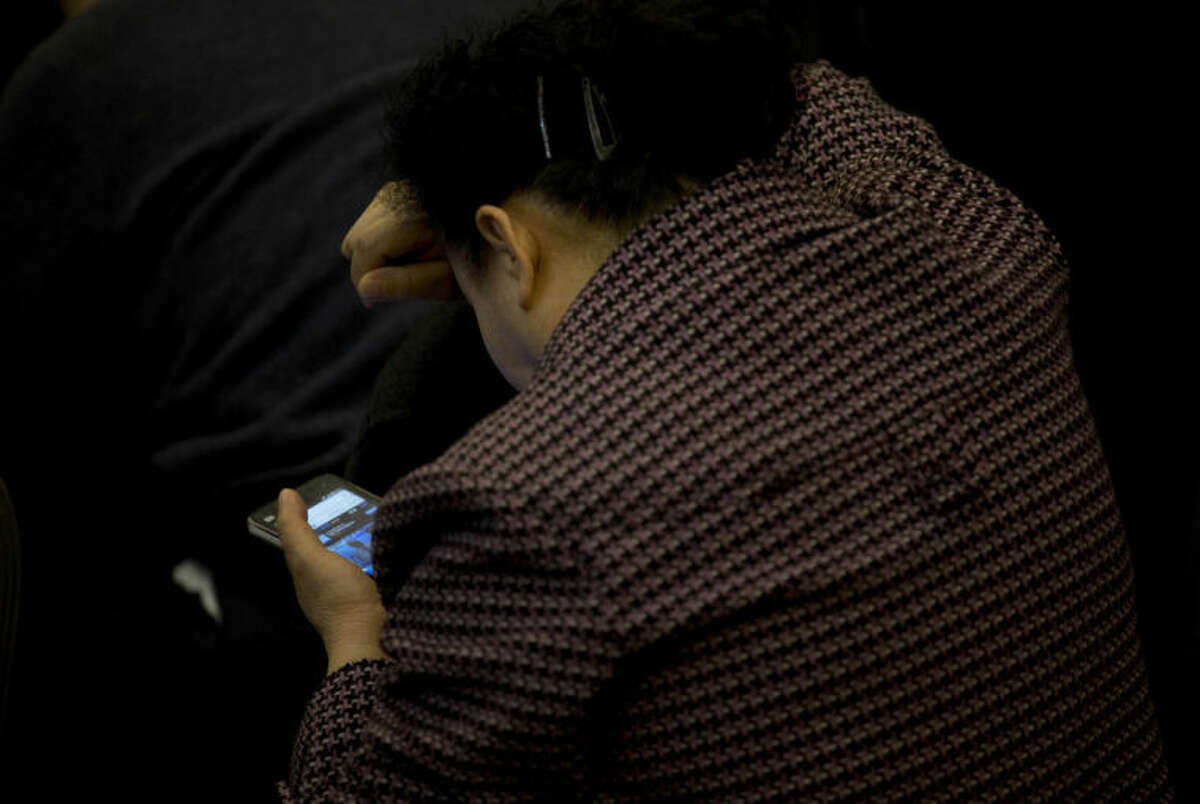 A relative of Chinese passengers aboard the missing Malaysia Airlines Flight MH370 uses her smartphone to watch a news conference held by the airlines' officials at a hotel ballroom in Beijing Monday, March 17, 2014. The search for the missing Malaysian jet pushed deep into the northern and southern hemispheres Monday as Australia took the lead in scouring the seas of the southern Indian Ocean and Kazakhstan - about 10,000 miles to the northwest - answered Malaysia's call for help in the unprecedented hunt. (AP Photo/Andy Wong)