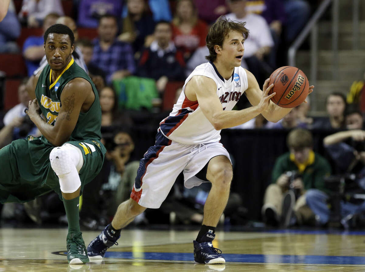 Gonzaga's Kevin Pangos, right, passes after he made a turn in front of North Dakota State's Kory Brown during the first half of an NCAA tournament college basketball game in the Round of 64 in Seattle, Friday, March 20, 2015. (AP Photo/Elaine Thompson)