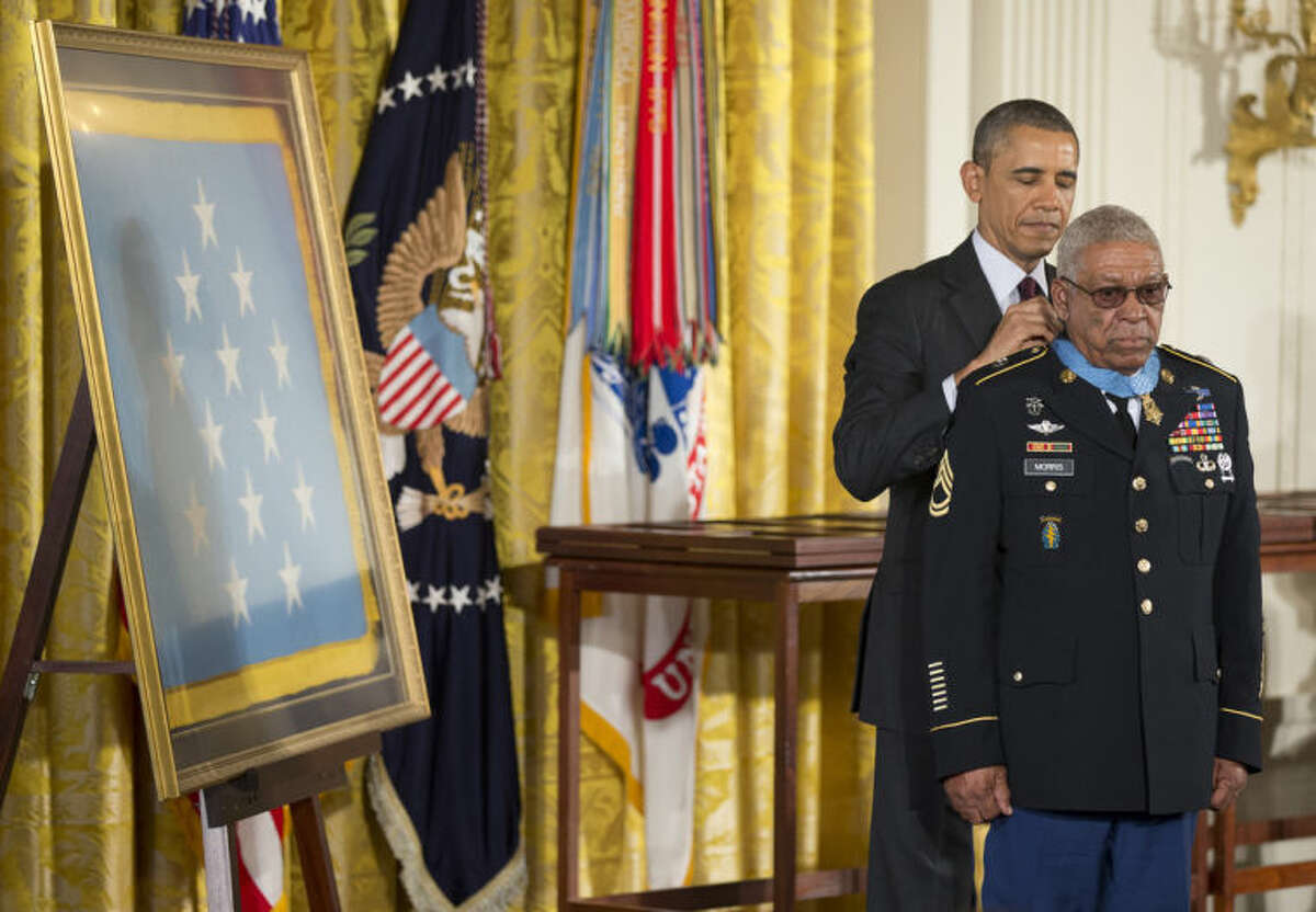 President Barack Obama awards Army Staff Sgt. Melvin Morris the Medal of Honor during a ceremony in the East Room of the White House in Washington, Tuesday, March 18, 2014. President Obama awarded the Medals of Honor to 24 ethnic or minority U.S. soldiers who performed acts of bravery under fire in three of the nation?’s wars, that were denied because of prejudice. (AP Photo/Manuel Balce Ceneta)