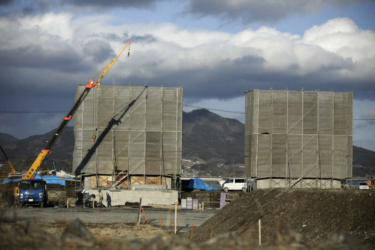 In this March 5, 2015 photo, workers build sea walls in Rikuzentakata, Iwate Prefecture, northeastern Japan. Four years after a towering tsunami ravaged much of Japan's northeastern coast, efforts to fend off future disasters are focusing on a nearly 400-kilometer (250 mile) chain of cement sea walls, at places nearly five stories high. (AP Photo/Eugene Hoshiko)