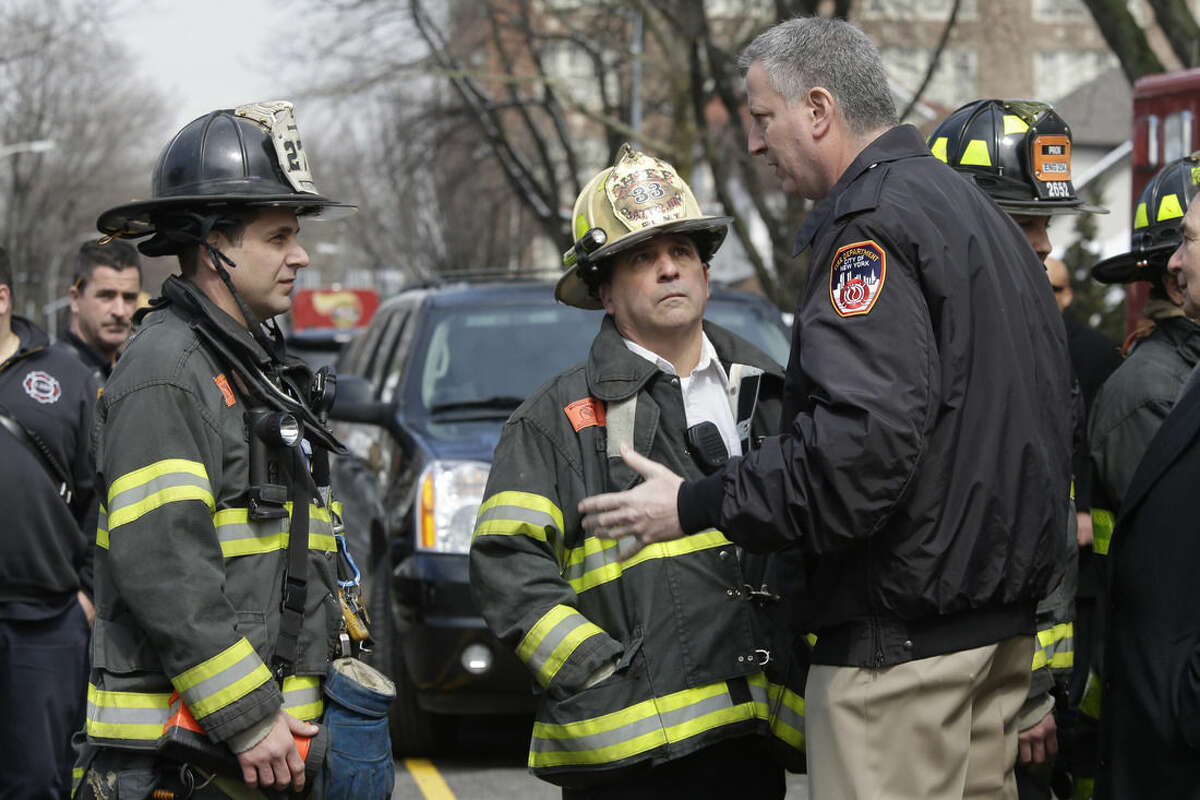 New York City Mayor Bill de Blasio, right, speaks to firefighters who responded to a fatal fire in the Brooklyn borough of New York, Saturday, March 21, 2015. The fire raged through the residence early Saturday, killing seven children and leaving two other people in critical condition, authorities said. (AP Photo/Mary Altaffer)