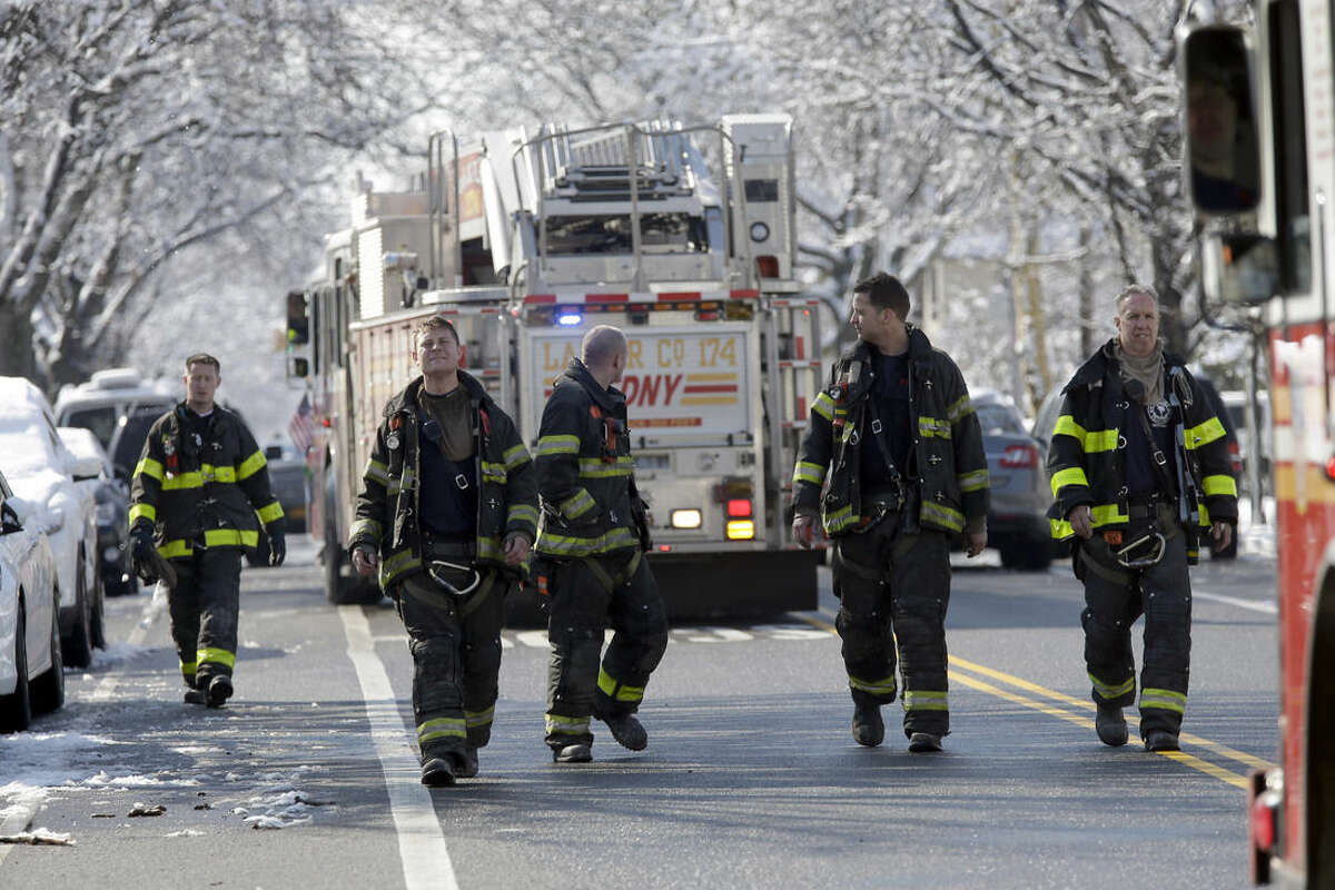 Firefighters leave the scene of an overnight fire in the Brooklyn borough of New York, Saturday, March 21, 2015. The fire raged through a residence early Saturday, killing seven children and leaving two other people in critical condition, authorities said. (AP Photo/Mary Altaffer)