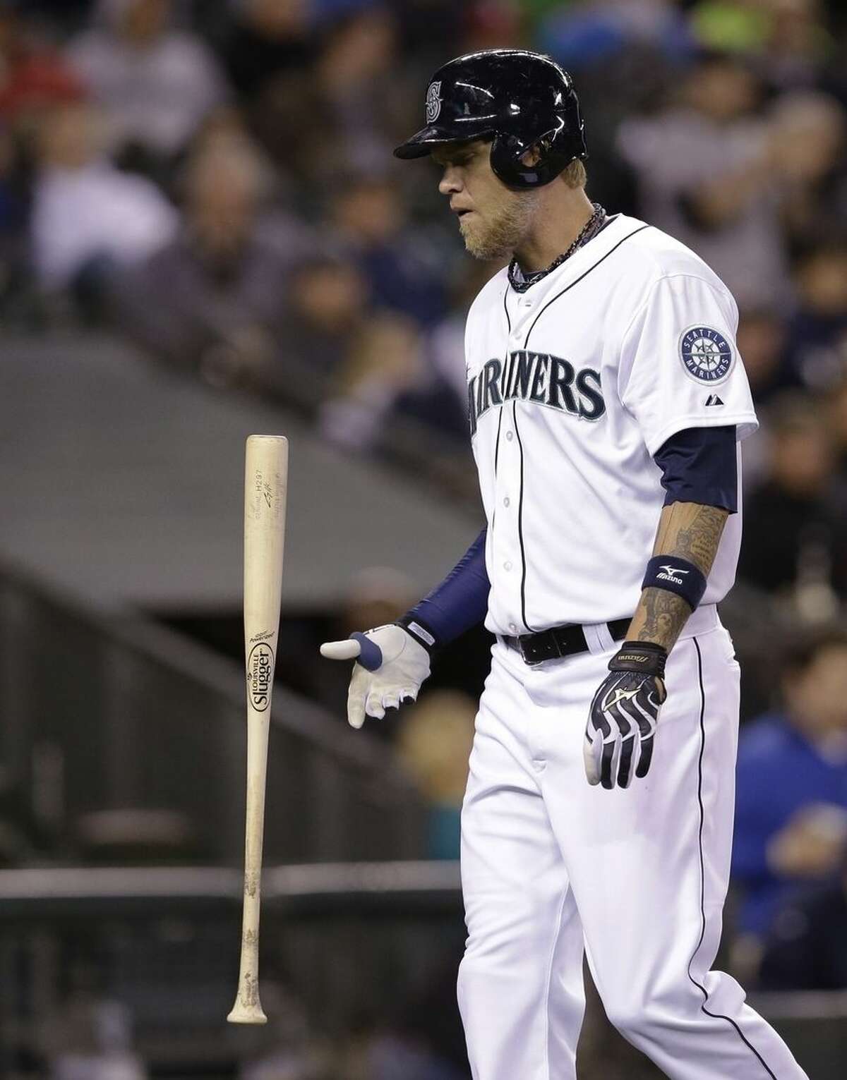 FILE - In this April 9, 2014, file photo, Seattle Mariners' Corey Hart flips his bat as he heads to the dugout after striking out against the Los Angeles Angels in the ninth inning of a baseball game in Seattle. The company that makes Louisville Slugger bats has announced a deal to sell the iconic brand to rival Wilson Sporting Goods Co. Wilson's deal to acquire the global brand, sales and innovation rights from Louisville Slugger's parent, Hillerich & Bradsby Co., still requires approval by H&B shareholders. Under terms of the agreement announced Monday, March 23, 2015, H&B will become Wilson's exclusive manufacturing partner for wood bats. H&B will continue to manufacture wood bats at its factory in Louisville, Kentucky. (AP Photo/Elaine Thompson, File)